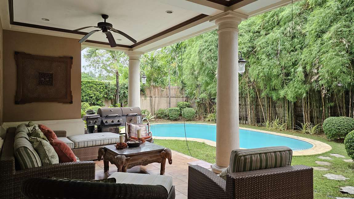 Covered poolside lanai with premium rattan lounge seating beside the swimming pool of the luxury Cebu home