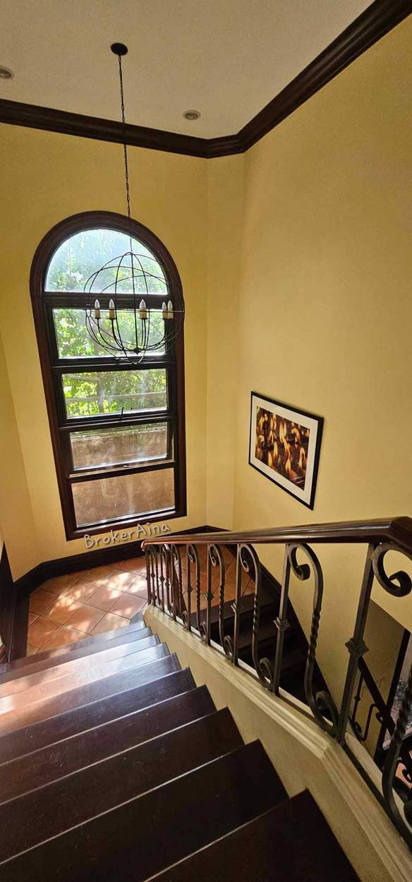 Hardwood staircase with wrought-iron balustrade and a tall arched window